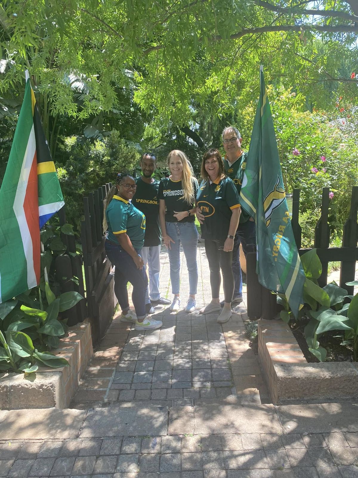The Dr MacKenzie Dental and Snugfit team in Springbok green and gold, flanked by South African flags on the practice garden pathway